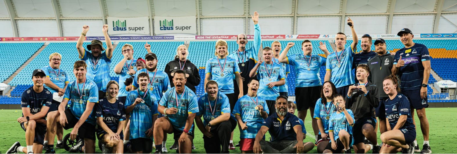 A group of diverse people in light blue sports uniform with medals around their necks. 