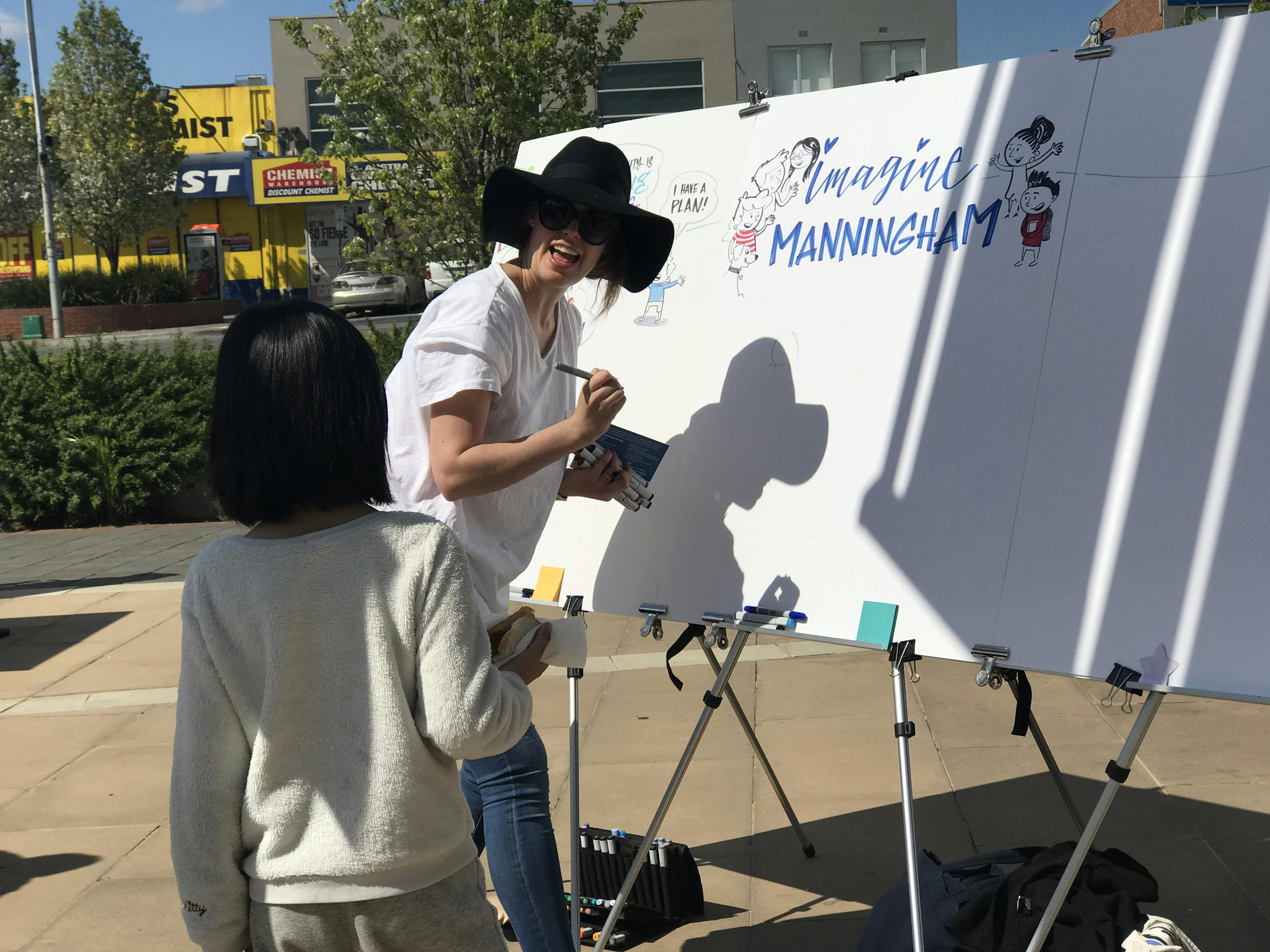 Child talking to graphic artist making an Imagine Manningham poster