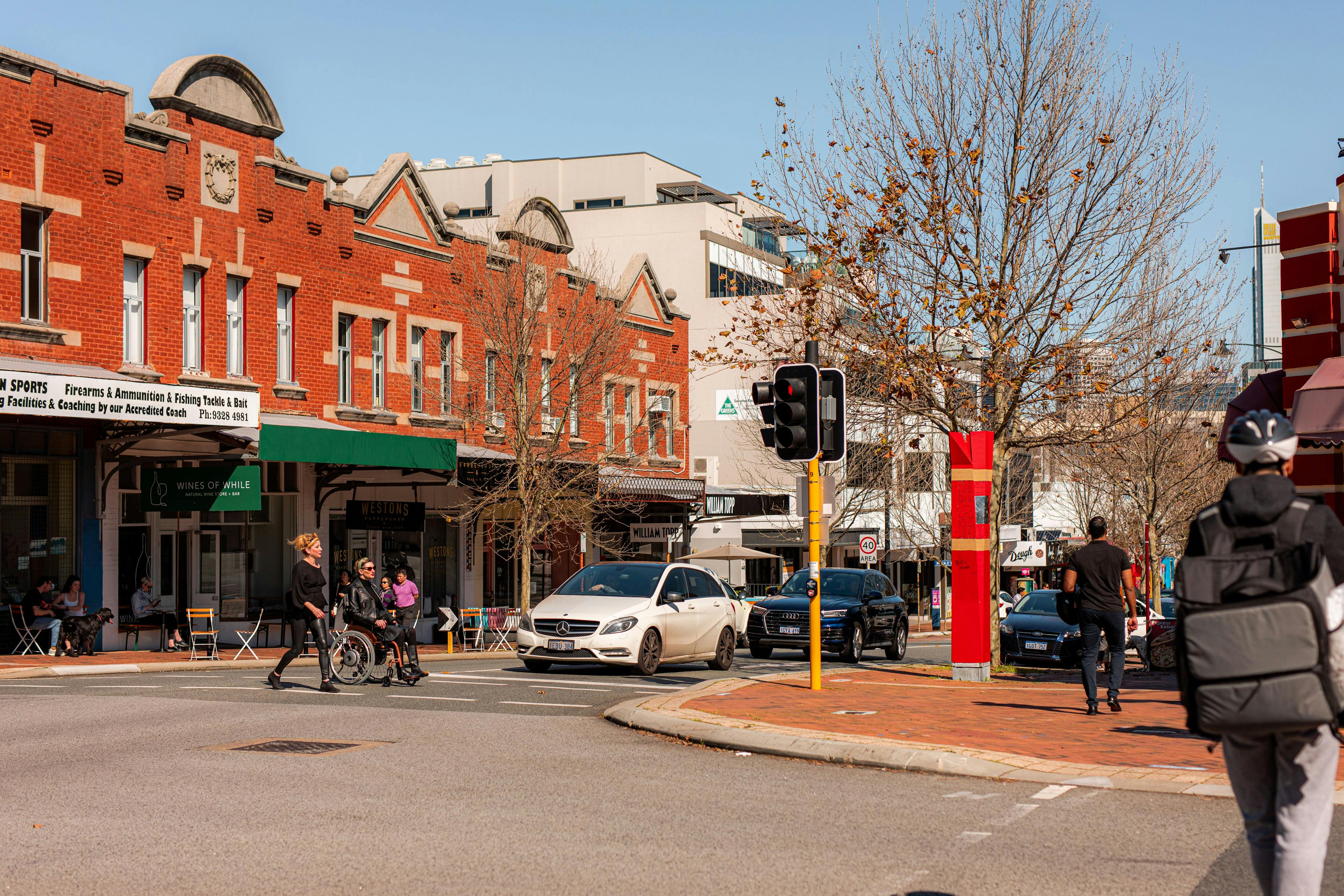 Pedestrians and wheelchair user crossing William Street at the traffic lights.