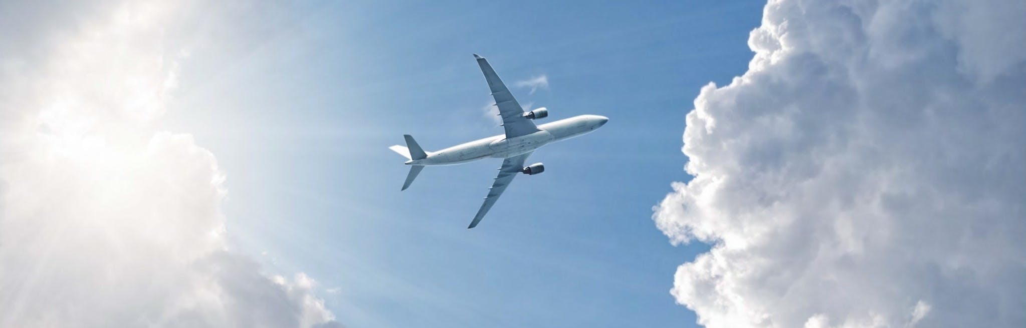 View from beneath of plane flying in blue sky and clouds