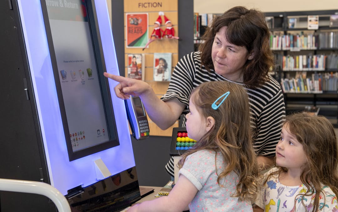 Family using digital kiosk to borrow library books