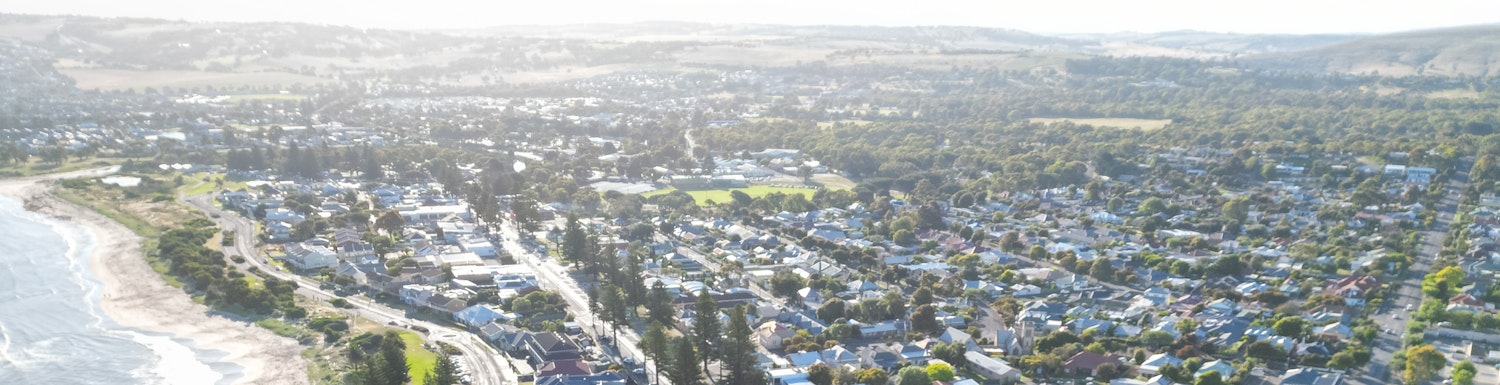 Aerial view of Victor Harbor showing coast and city centre with rolling hills in the backdrop