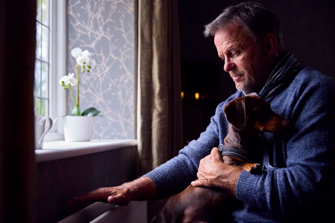 Man holding dog in window