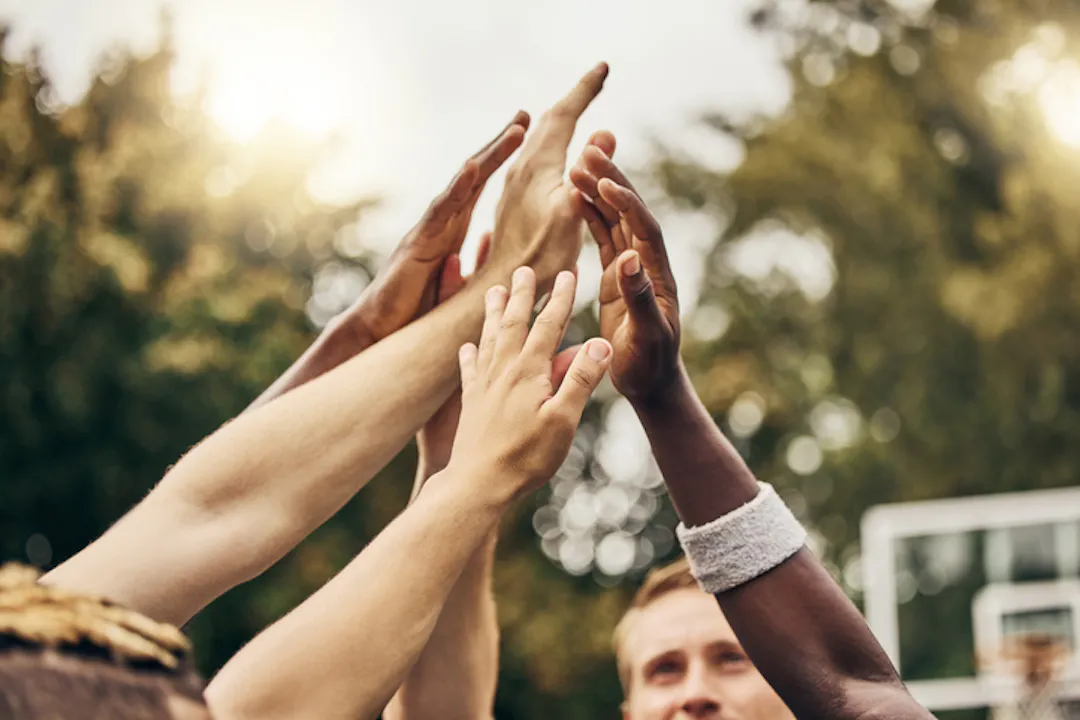 Multiple hands of sport players high fiving
