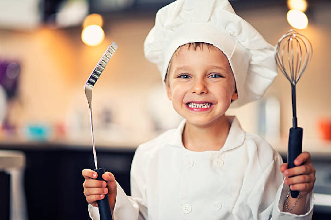 Boy in chef outfit holding cooking tools