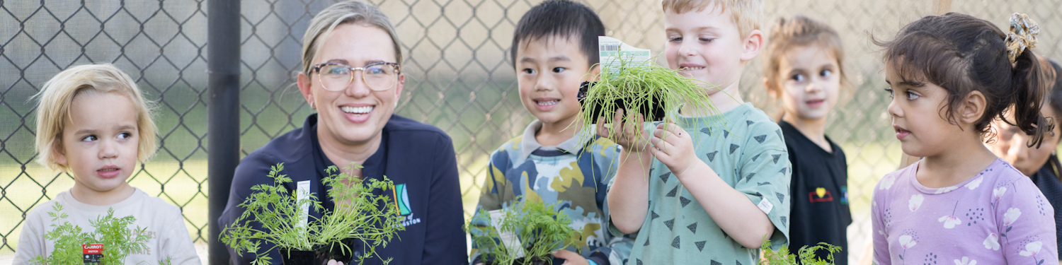 Kindergarten children and educator with potted plants