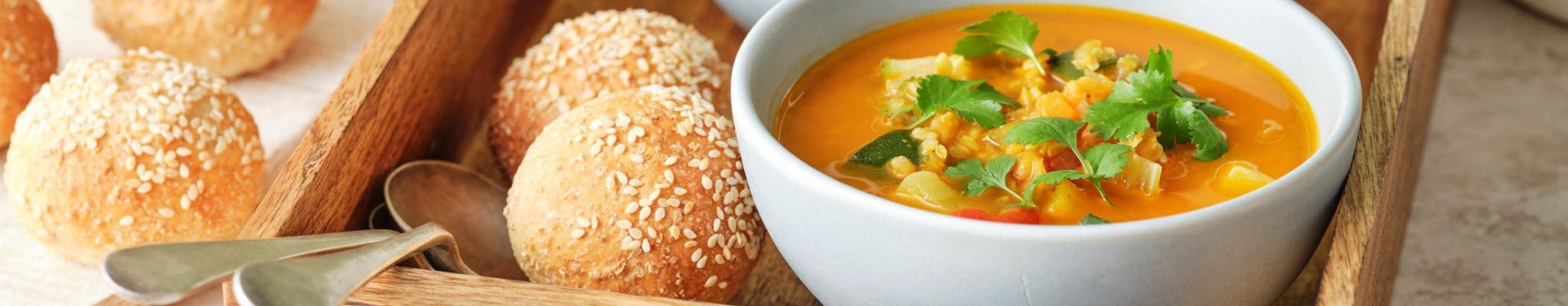 Two bowls of soup with bread ro