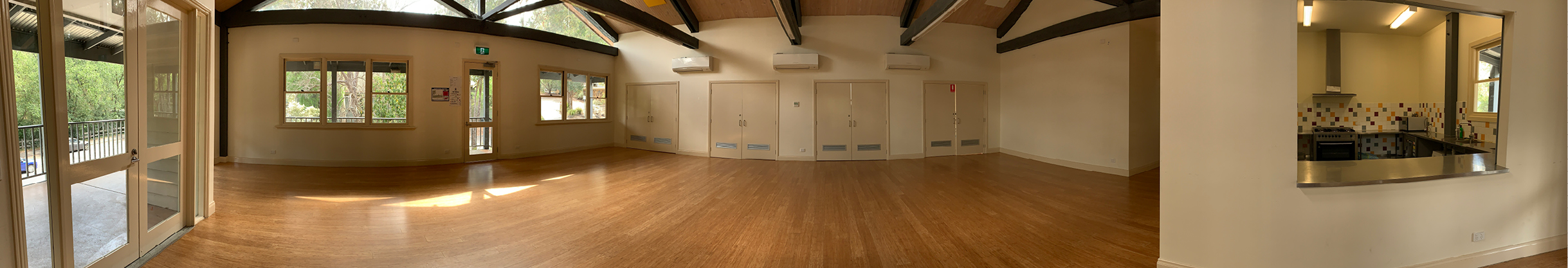 Picture of inside Warrandyte Community Centre, a room with windows, floor boards and a kitchenette 