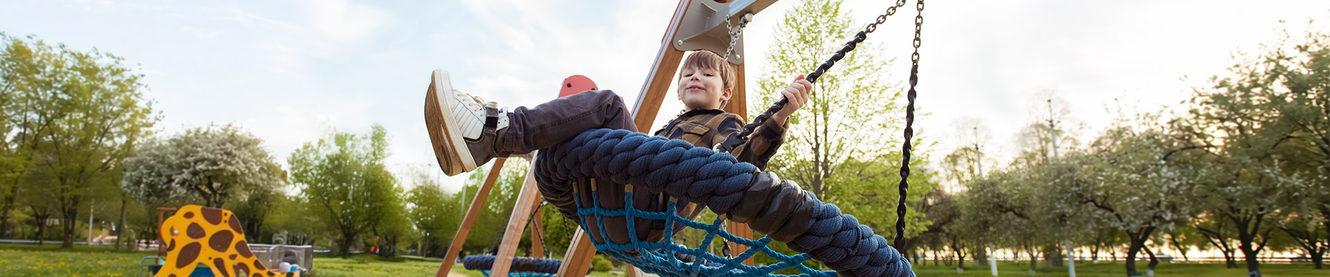 Young boy smiling on a swing in a park