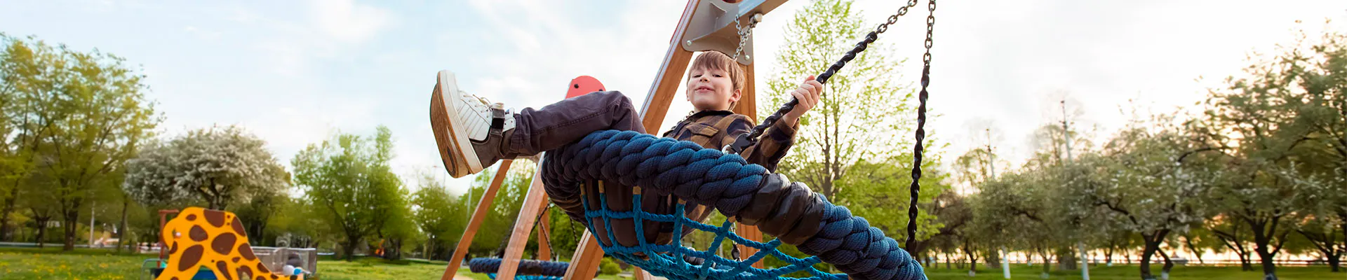 Young boy smiling on a swing in a park