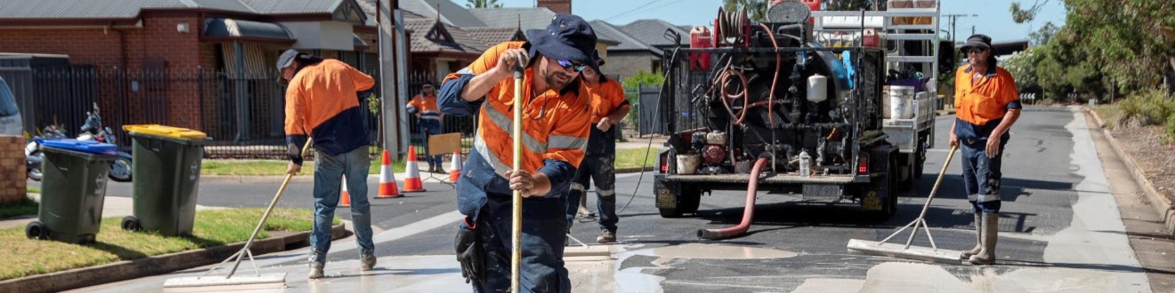 Image of workmen painting a road light grey in Charles Sturt City Council