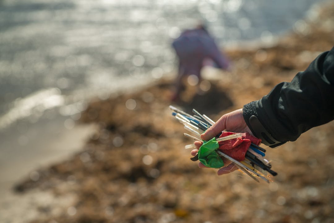 Beach clean up - plastics Image of a hand holding plastic and rubbish collected from the beach.