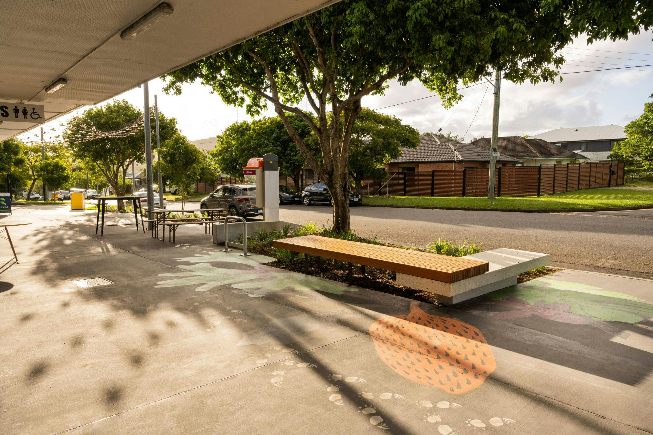 Seating area with new platform seat, planting bed, bike rack, accessible phone box and upgraded concrete footpath with colourful 'Echidna Magic' pavement design. 