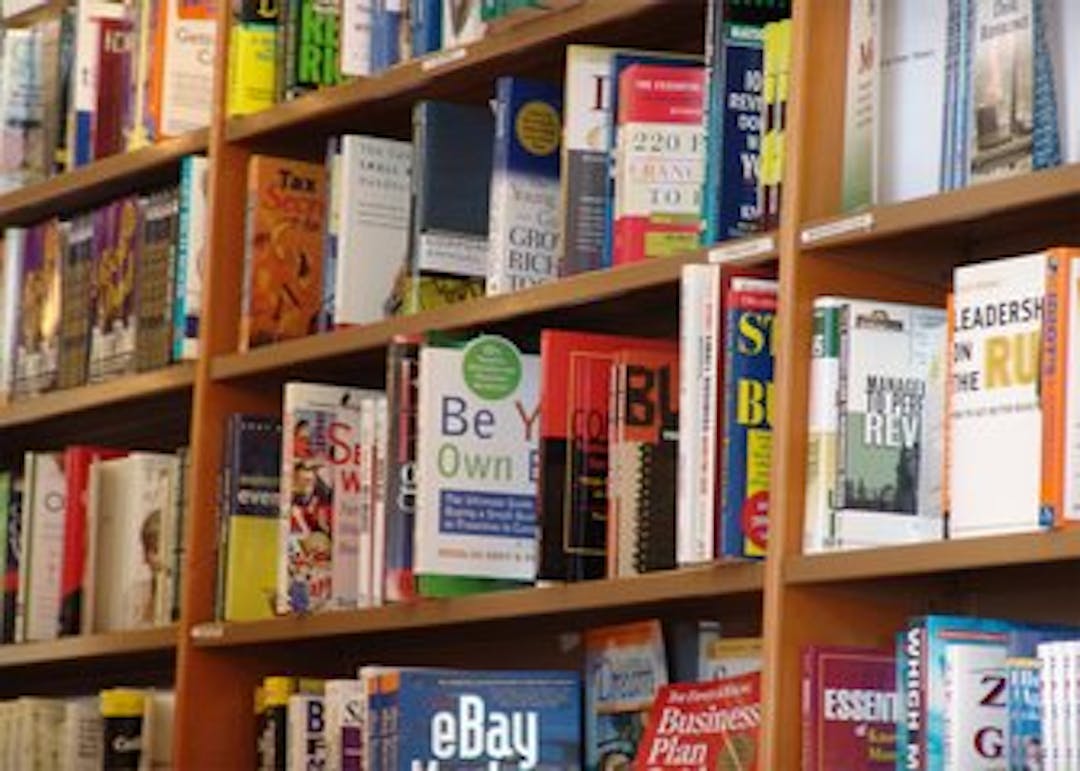 Rows of books are displayed on a library book shelf.