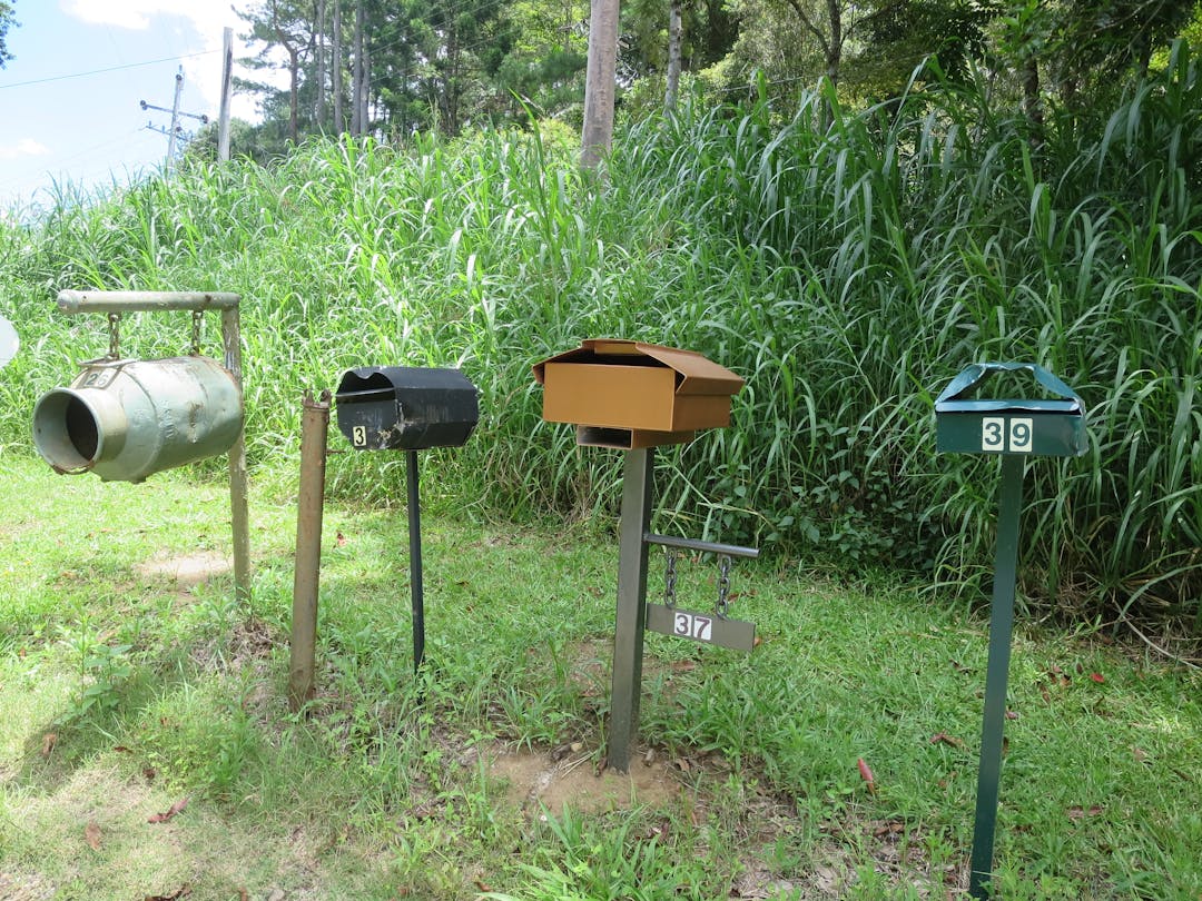 Four letterboxes at the entrance to a rural property.