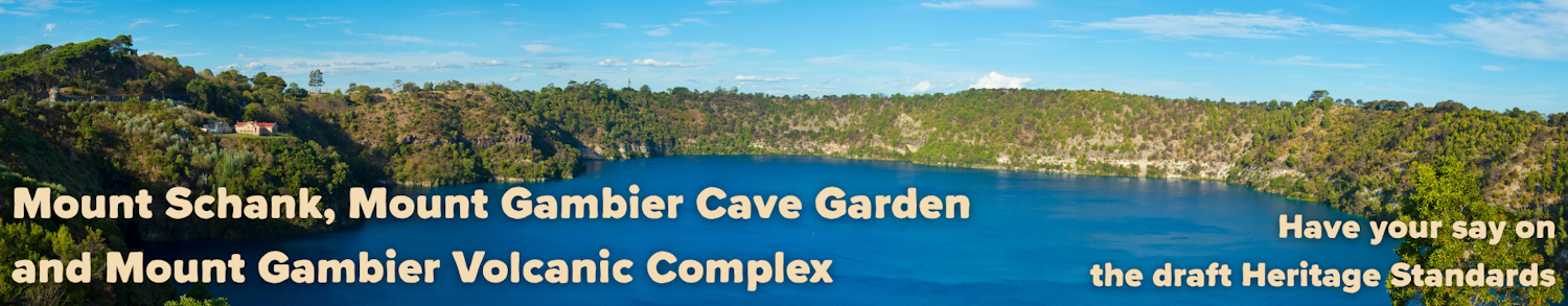 Wide view of Blue Lake, an extinct volcano crater filled with blue water, with green vegetation around the ridge