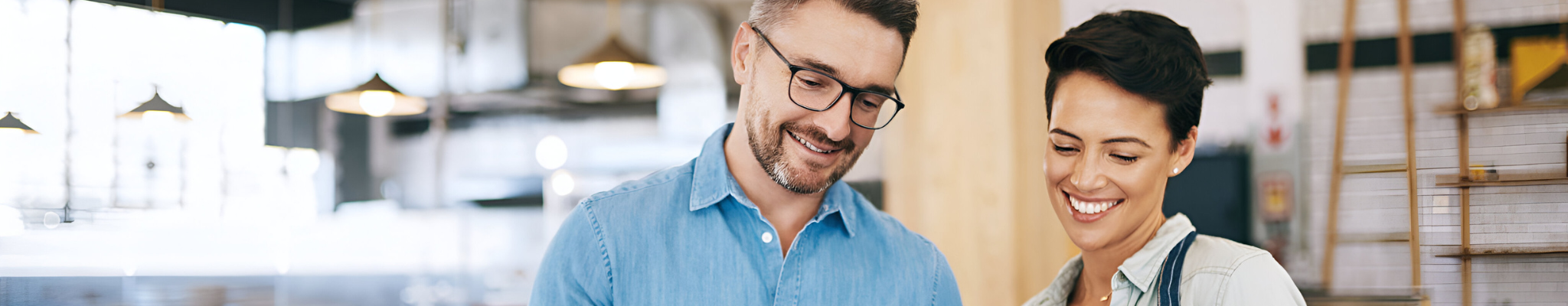 Two business owners in their cafe business looking down at an electronic tablet