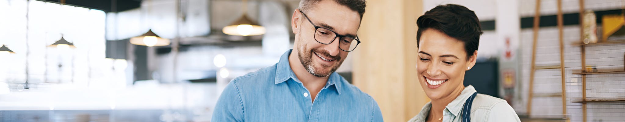 Two business owners in their cafe business looking down at an electronic tablet