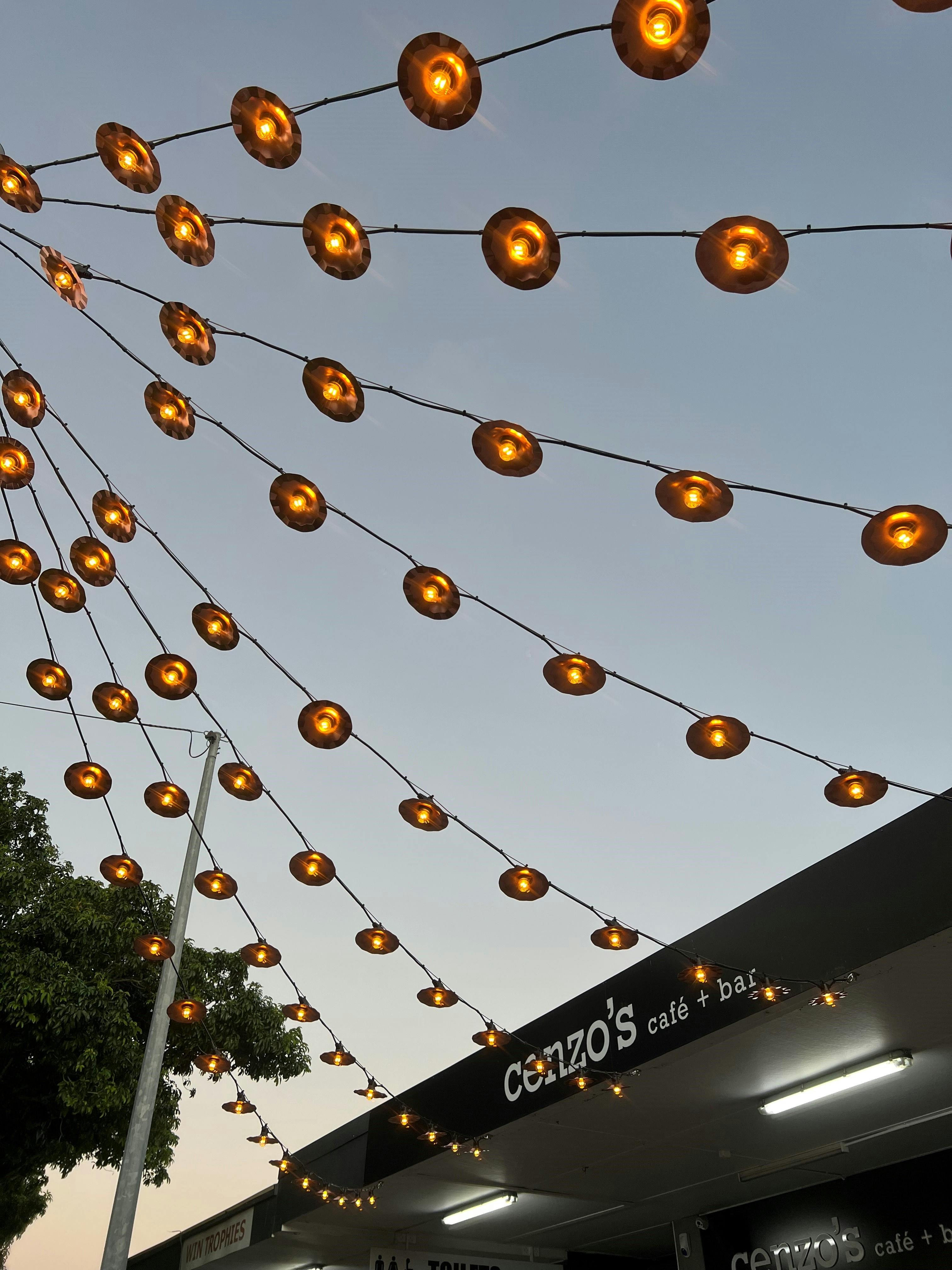 Close up of the new catenary lighting showing the warm glow of the lights against the dusk sky.