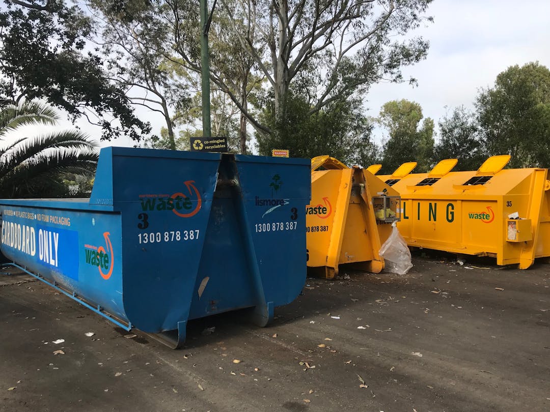 This is a graphic of three large skip bins at the recycling drop-off centre on Brewster Street. One blue and two bright yellow.