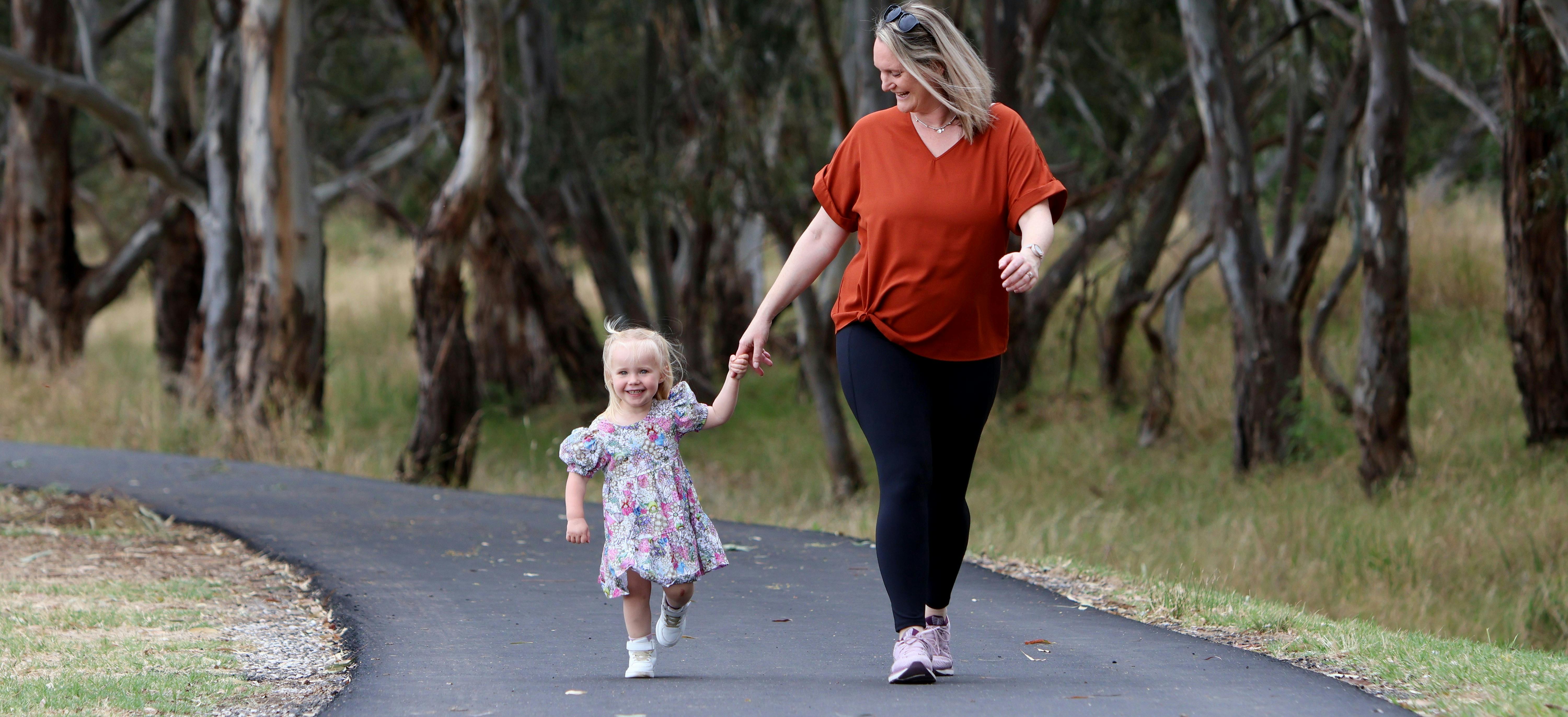 Girl and adult holding hands on walking trail