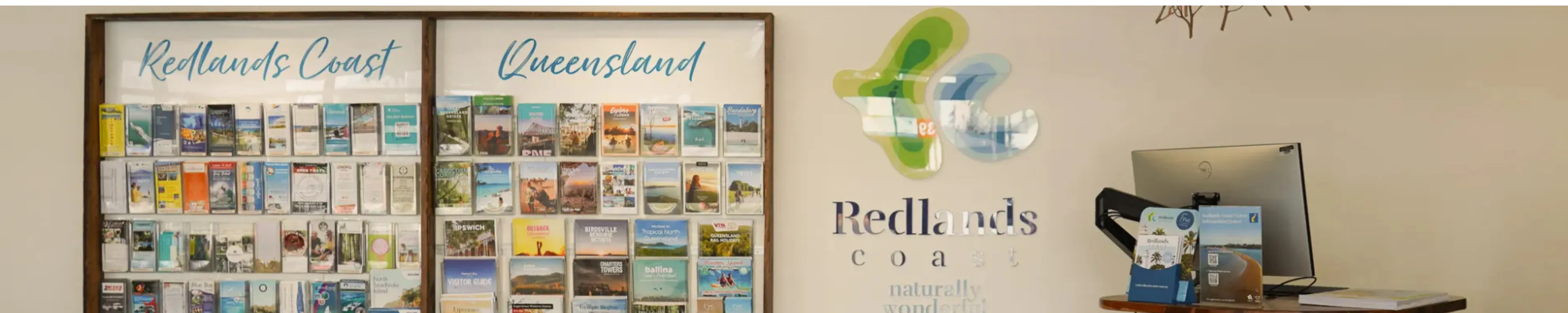 A picture of the foyer of the Visitor Information Centre. Tourism flyers are neatly displayed on the wall.