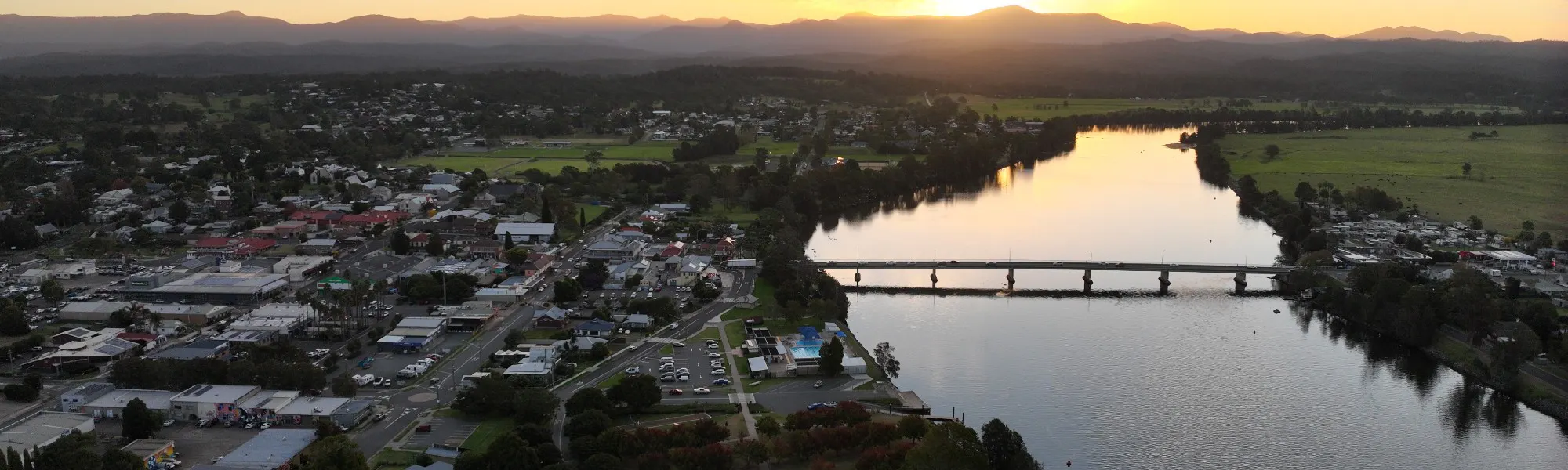 Aerial image of a river with houses on either side and a bridge crossing over the river