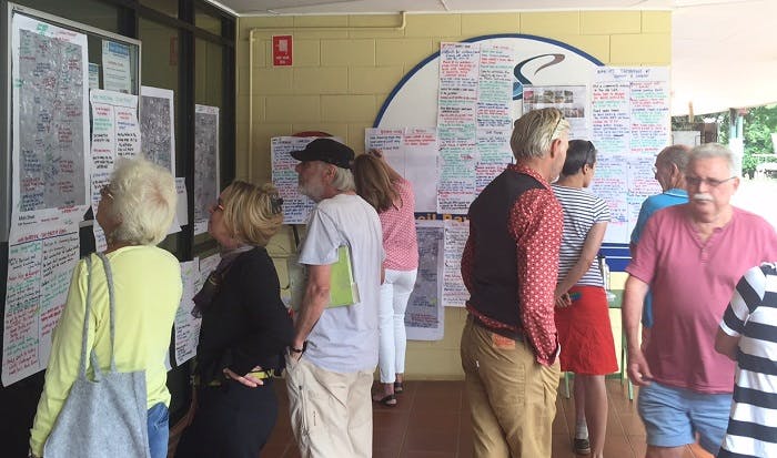 People reading hand-written engagement responses posted on walls at Tamborine Mountain