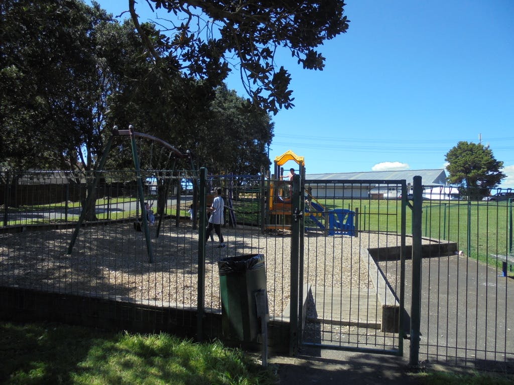 Fulling fenced playground contains swings and a basic play module at Kohuora Park.