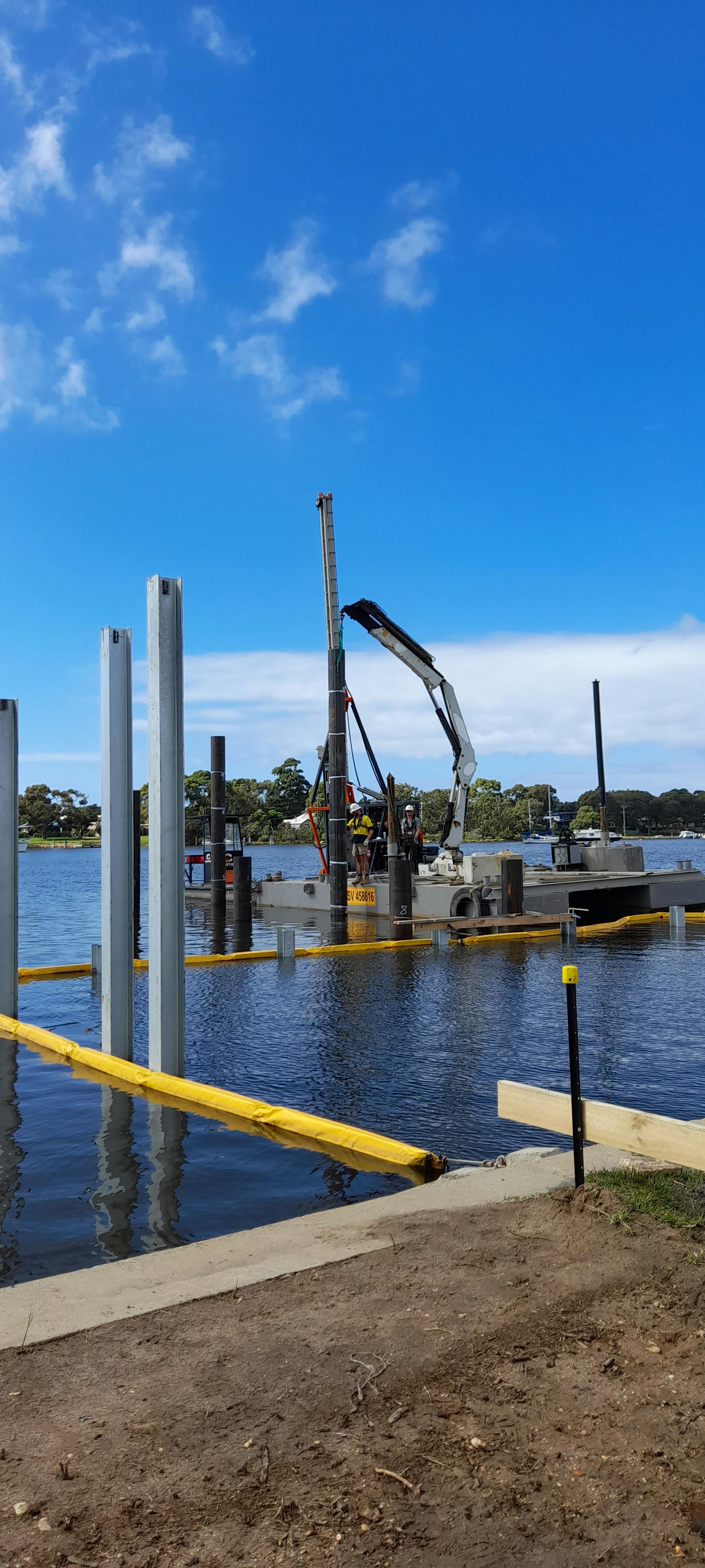 jetty construction - contractors on the barge installing the jetty piles and seawall pilons
