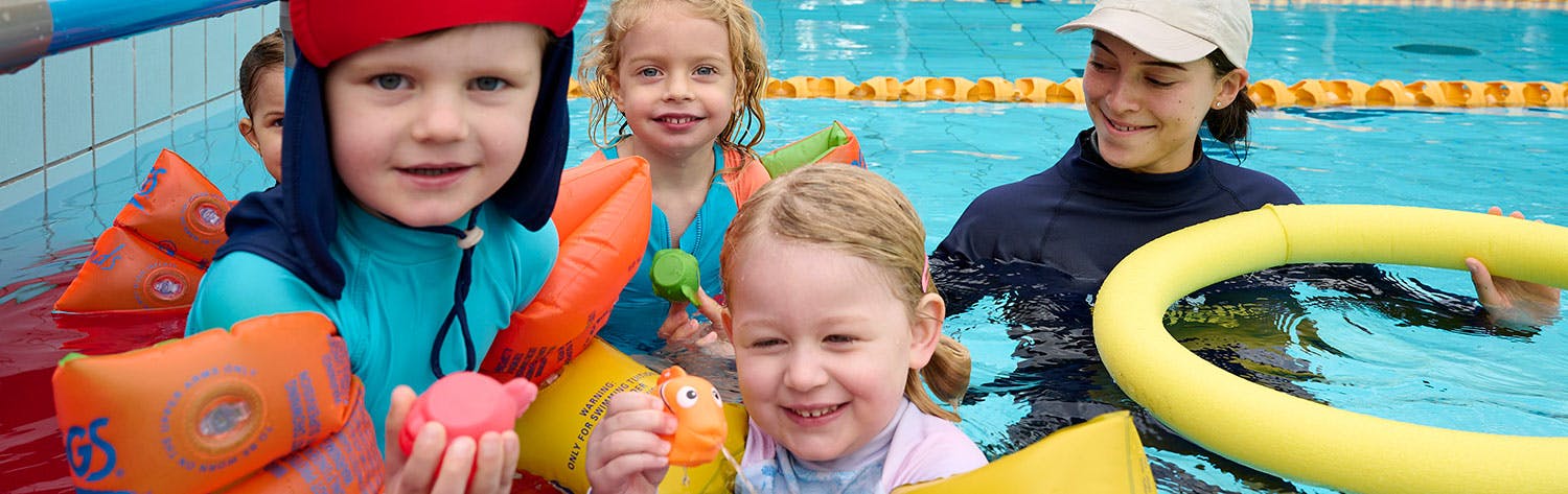 smiling kids and swimming instructor in swimming pool