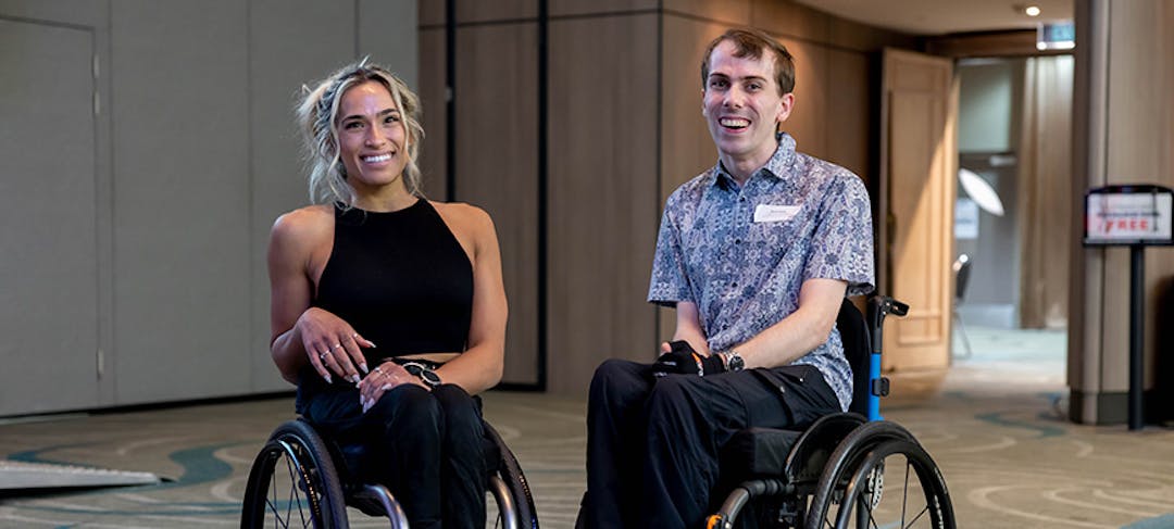 Madison de-Rosario and Daniel Clarke, two wheelchair users smiling in front of a beige background