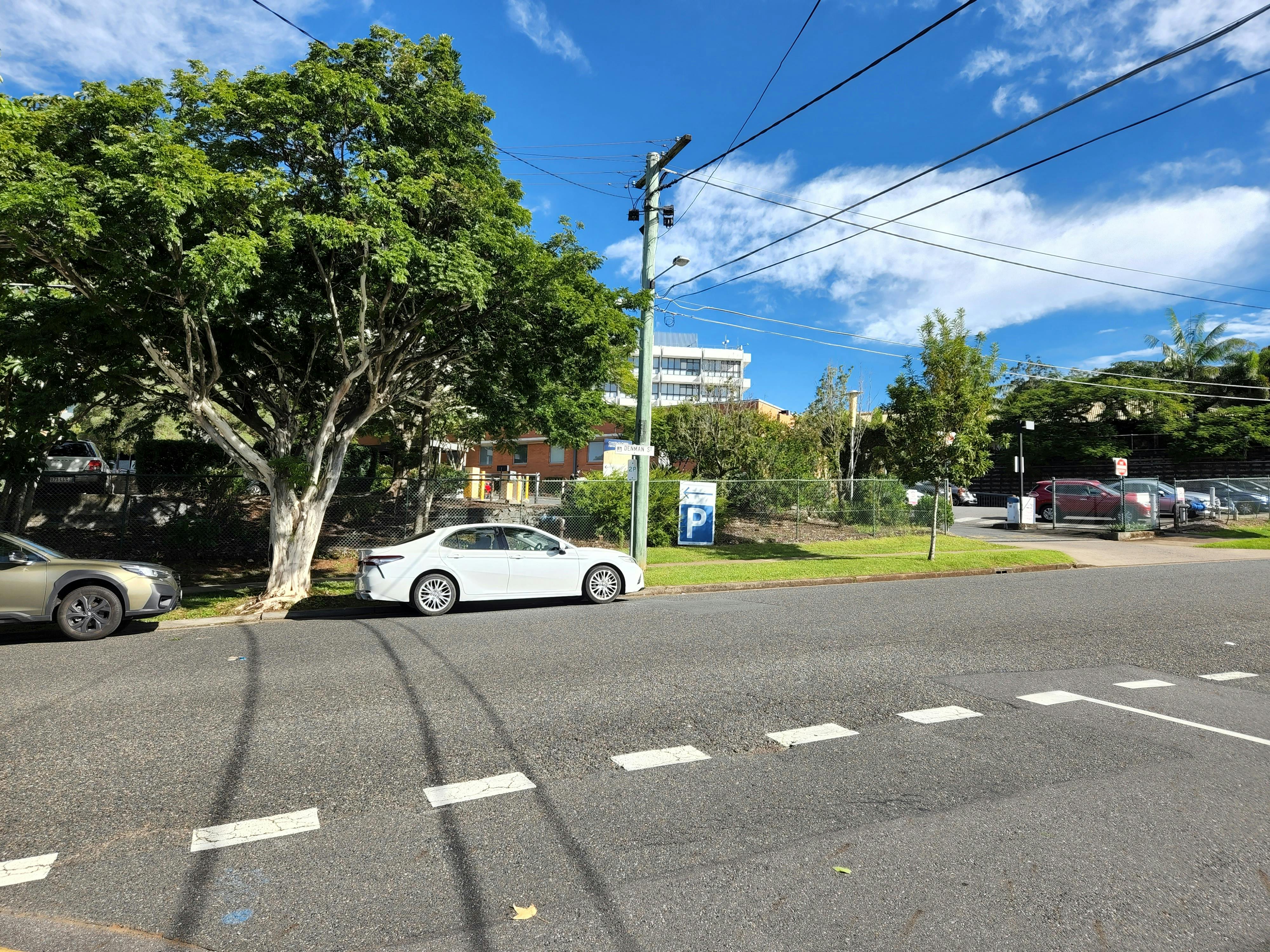 Another photo of cars parked on Denman Street, Greenslopes beside the exit to one of the Greenslopes Private Hospital carparks.