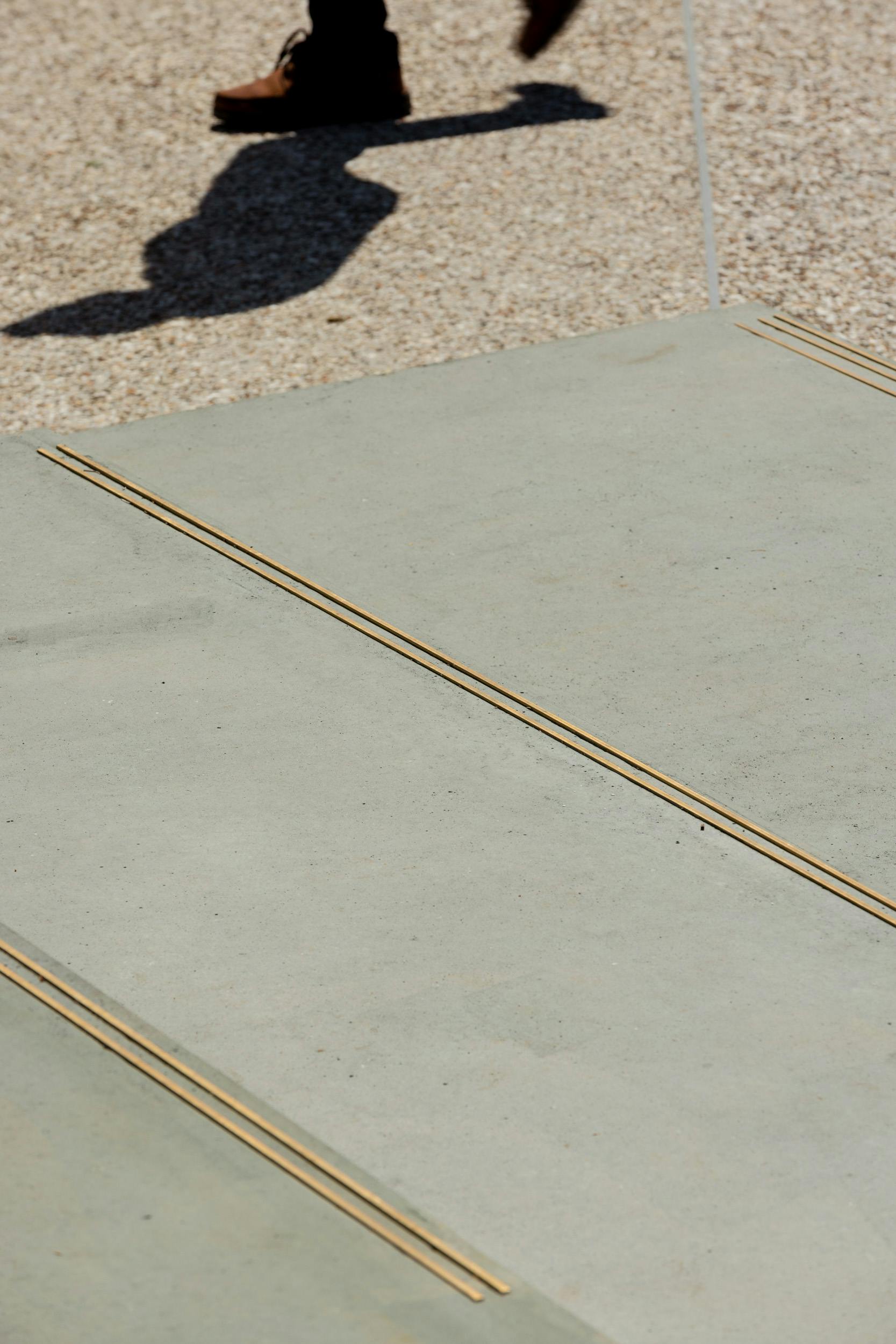 Detail view of concrete platforms, integrated brass nosing strips and exposed aggregate pavement - 01