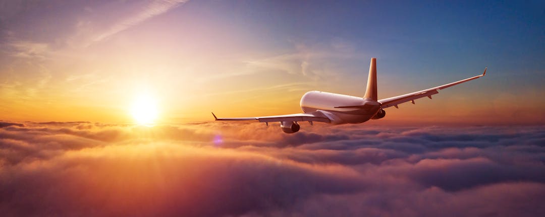 Sunset view of airplane over clouds. Aviation technology and world travel concept.
