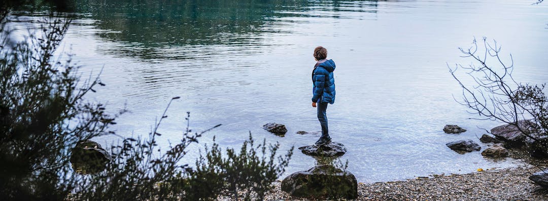 Boy standing on rocks in water at Bob's Cove, Queenstown
