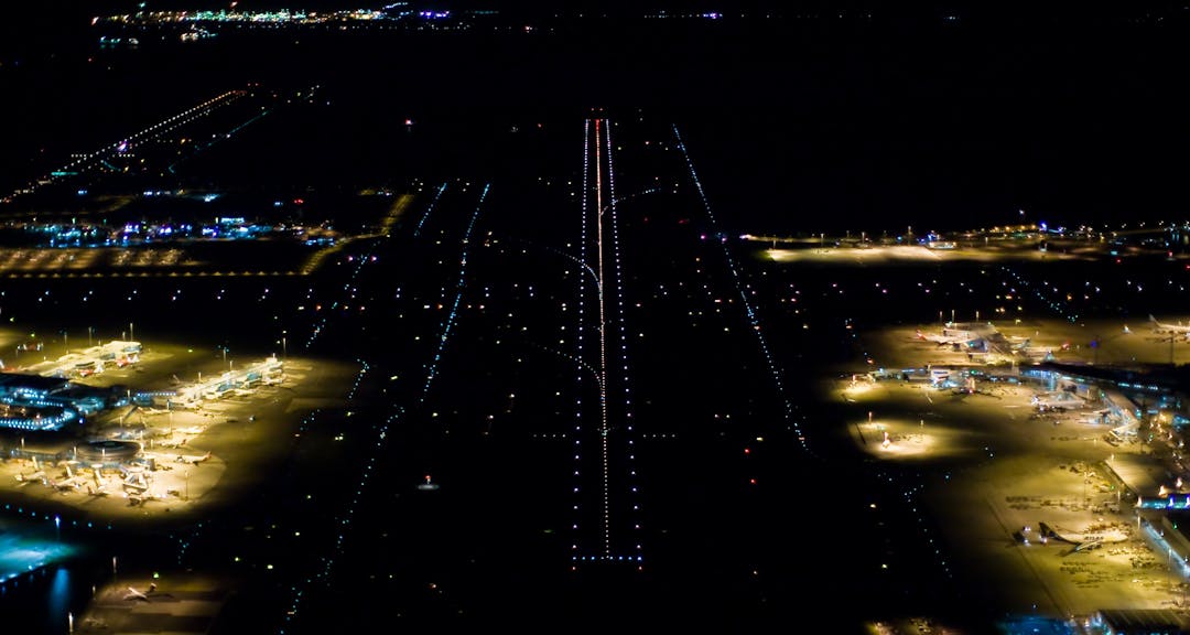 Night view of runways at Kingsford Smith International Airport (Sydney Airport), Sydney, New South Wales, Australia with runway lighting and parked planes visible