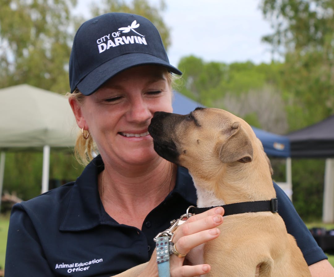 Council officer smiling holding a golden puppy 