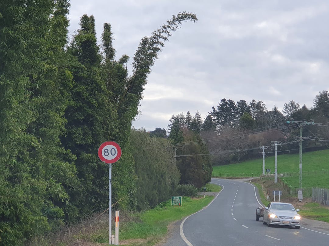 Image of a car on the road with 80km/h sign. 