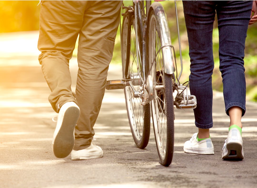 A man and woman walking their bike on a shared pathway.
