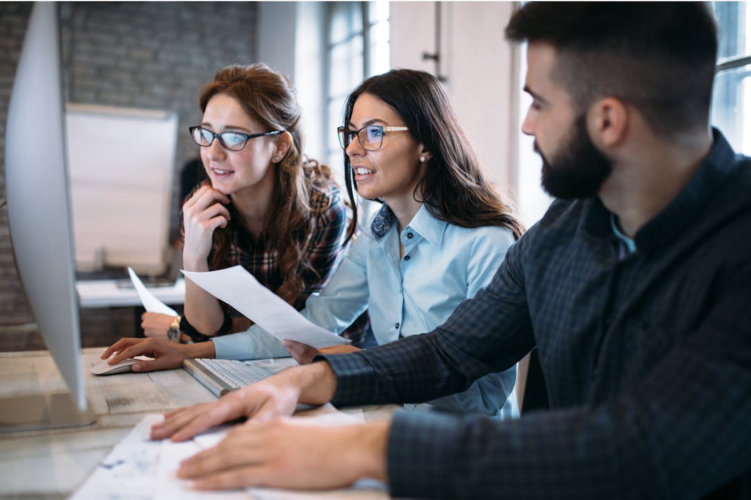 Two females and one male working together on a computer