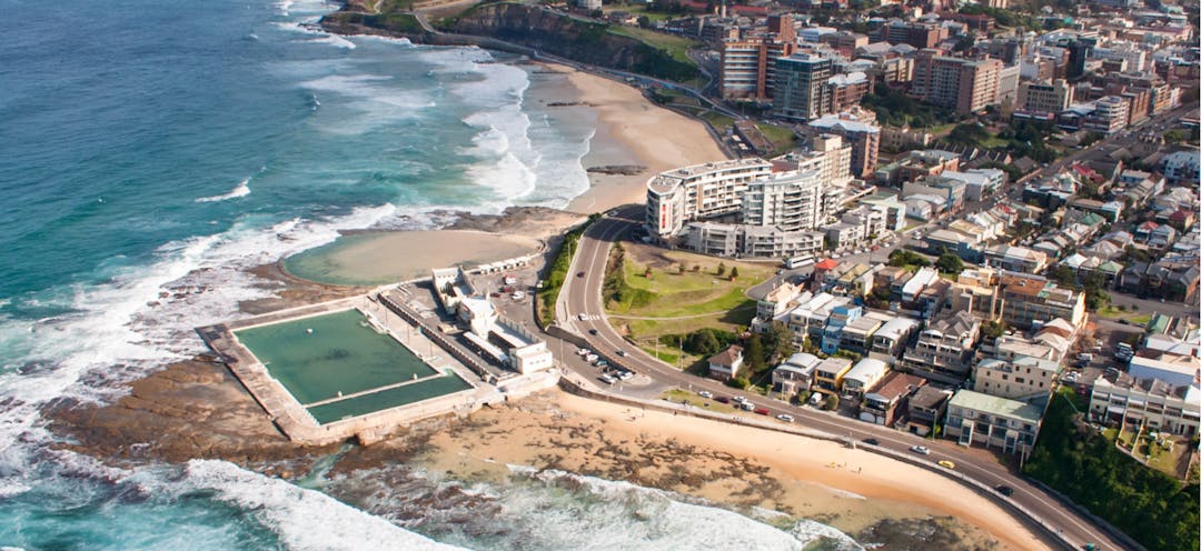 An aerial view of Newcastle Beach and Ocean Baths showing the city of Newcastle in the background