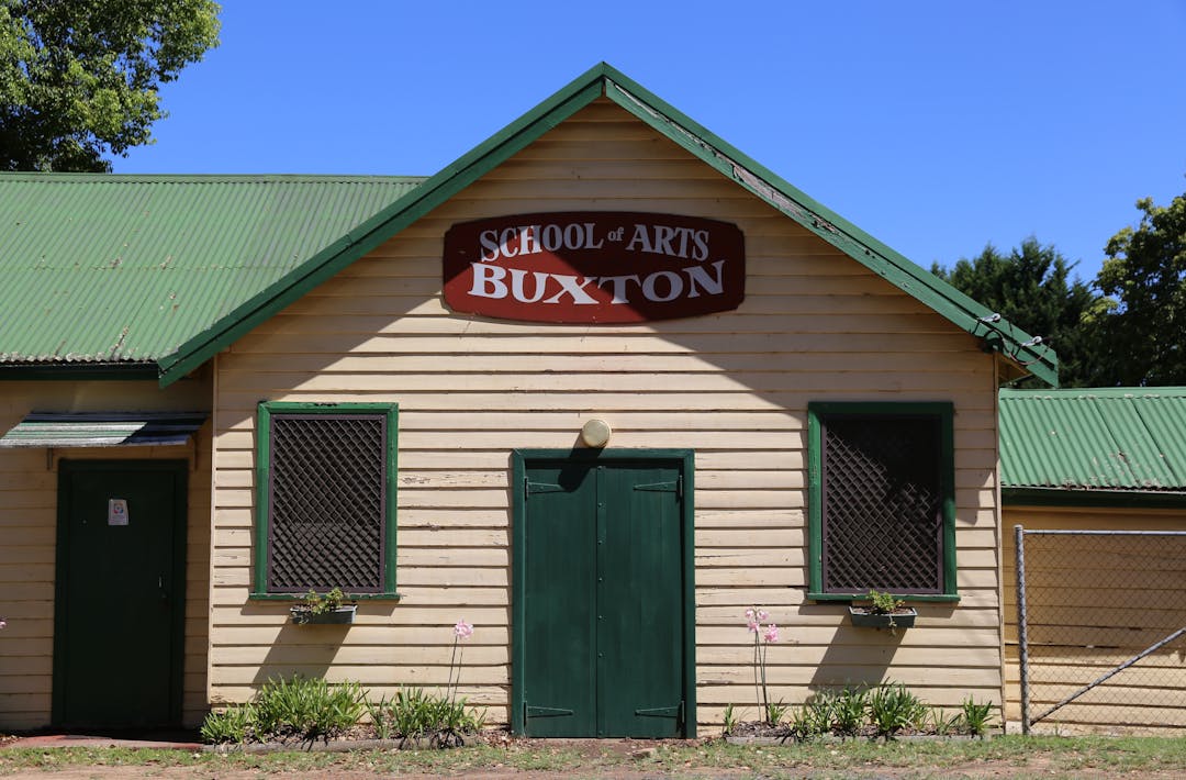 A tin-roof building with the sign "Buxton School of the "Arts"