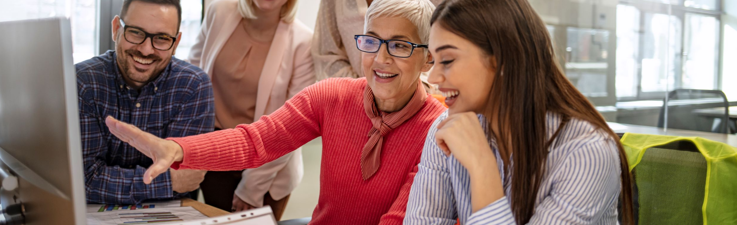 Group of people working together and looking at a computer screen - diverse ages, gender and race