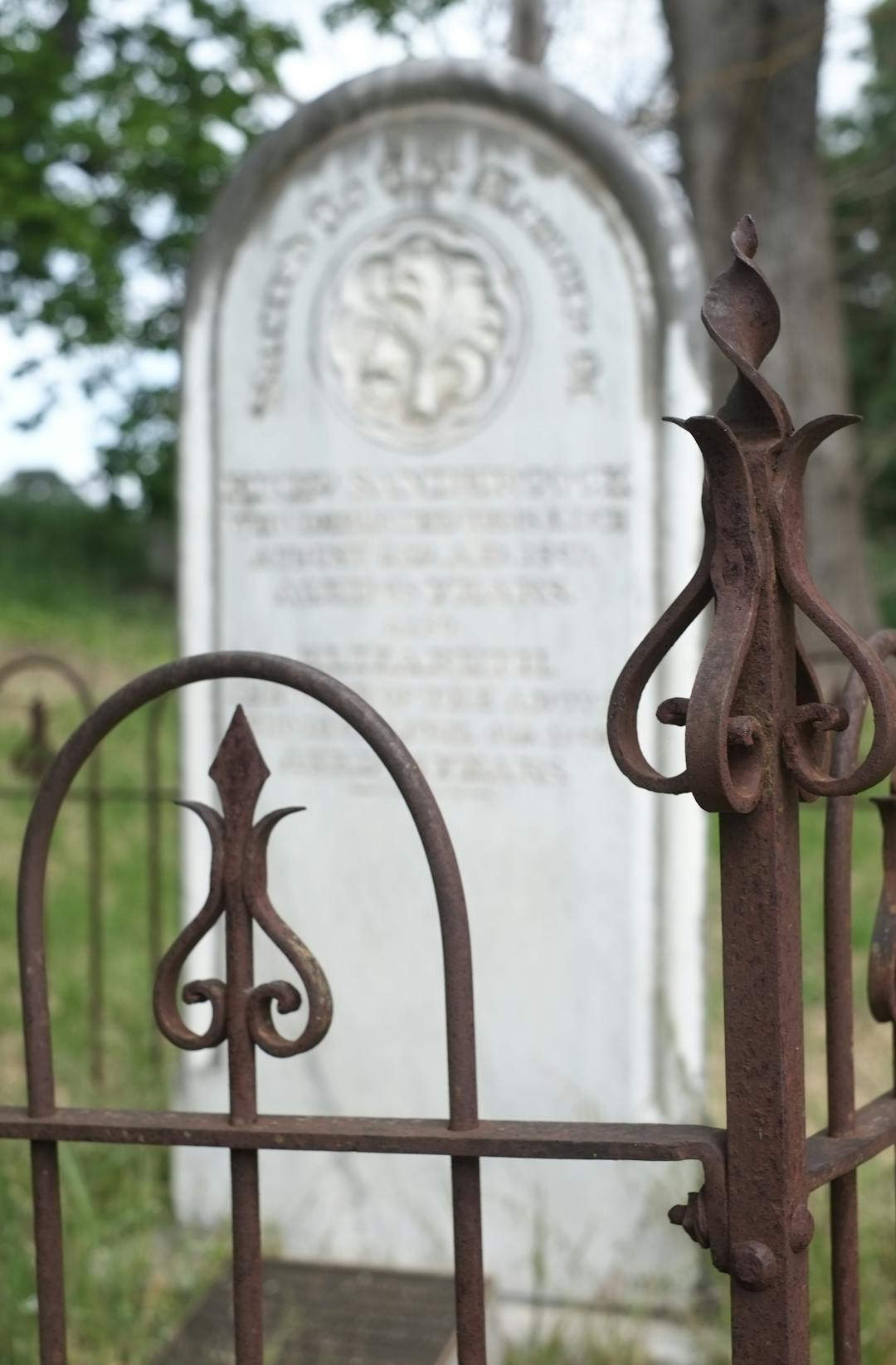 Cemetery headstone behind wrought iron