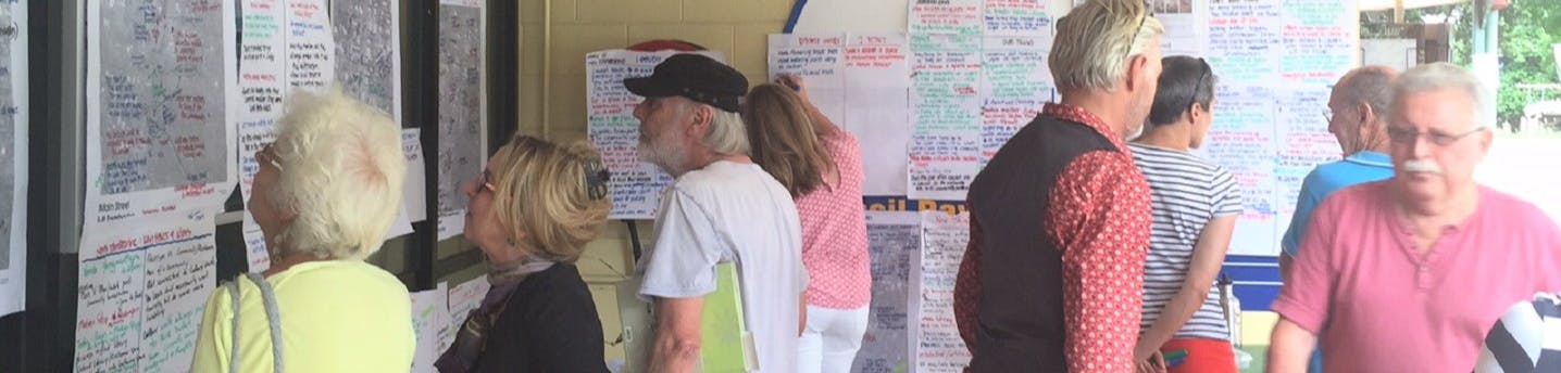  A group of people reading  handwritten information and ideas  on display about a Council project. Courtesy of John Mongard 