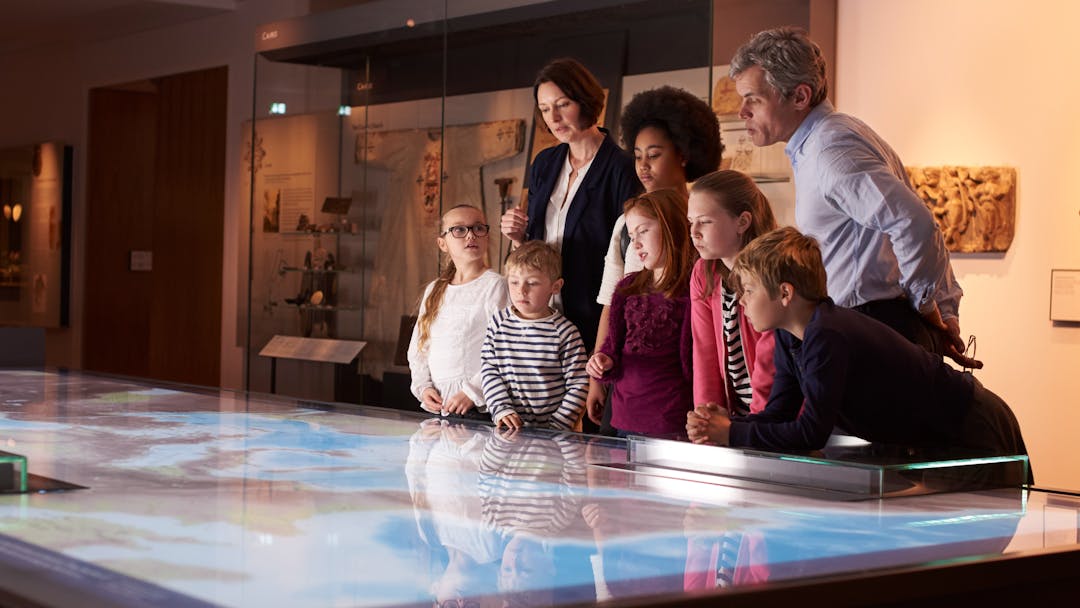 Photo of teachers and children looking at a map in a museum.