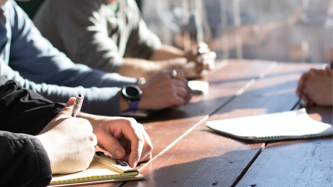 People having a discussion around a table with notepads