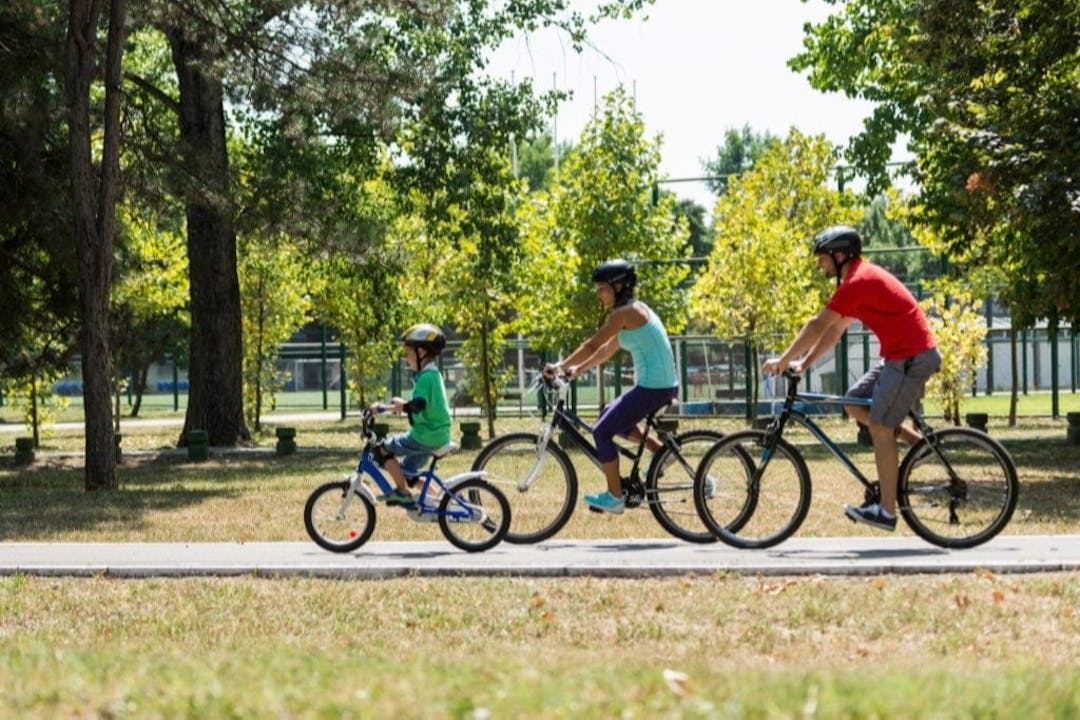 A family cycling along a path in a local park