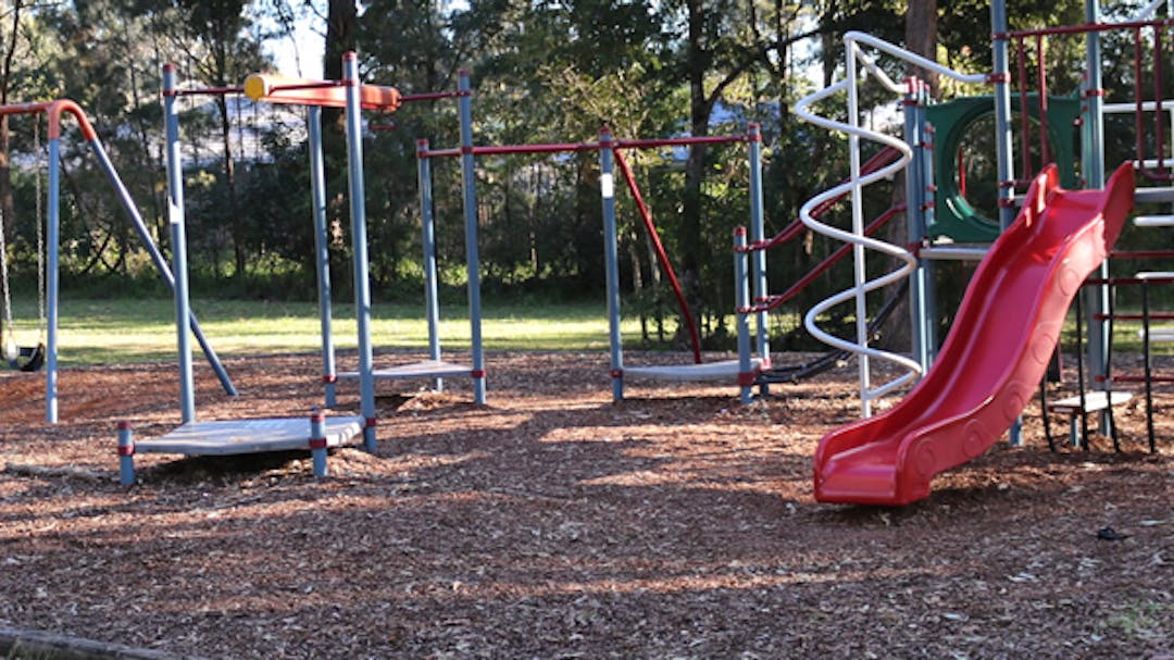 A playground with a slide, climbing equipment and swings